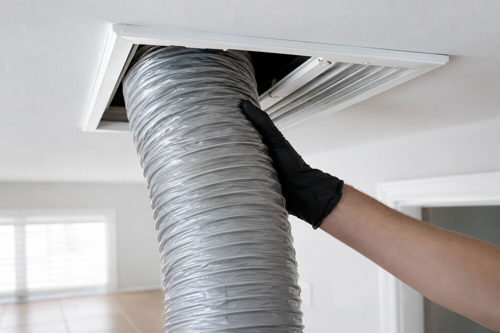 Technician with HEPA-filtered vacuum hose connected to a home's return duct register during a residential air duct cleaning